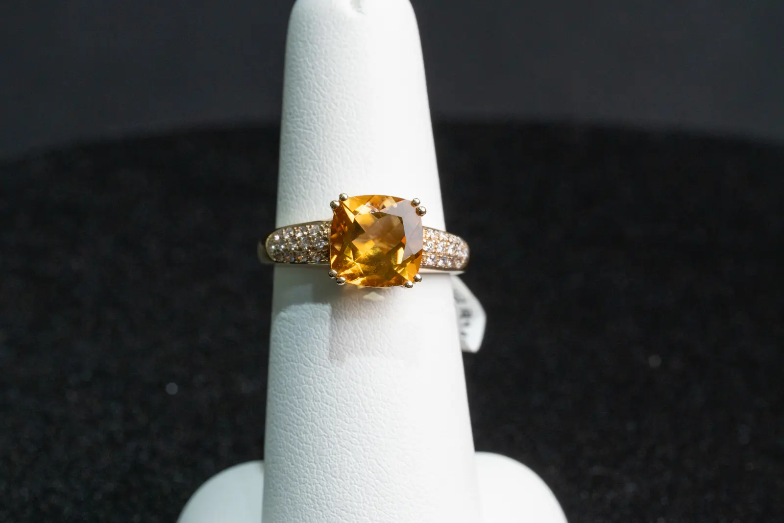 Shoot still from Ell's Jewelry: a cushion-cut citrine ring in rose gold on a white ring stand